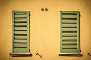 Two green shutters on a yellow wall