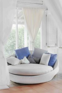 White interior shutters behind a white couch with blue pillows